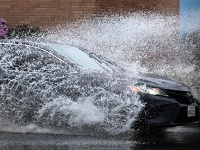 A car drives in the rain through storm water during a winter storm Los Angeles, California, on March 14, 2023. (Photo by Patrick T. Fallon / AFP)