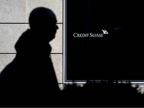 A man is seen in silhouette walking past a branch of Switzerland's Credit Suisse bank in Vevey, western Switzerland, on March 15, 2023 - Credit Suisse shares were in freefall on March 15, 2023 on the Swiss stock exchange, plunging 20 percent in morning trading to historic new record lows. (Photo by Fabrice COFFRINI / AFP)