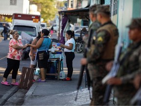 Women sell snacks on a street of Las Margaritas neighborhood during an anti-gang patrol following a year-long state of emergency against gangs, in Soyapango, El Salvador March 24, 2023.