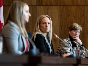 Conservative MP Karen Vecchio, right, and Kim Shore, centre, listen to Amelia Cline speak, as members of the group Gymnasts for Change Canada participate in a news conference on sexual misconduct allegations at Gymnastics Canada in Ottawa, on Tuesday, Nov. 22, 2022.