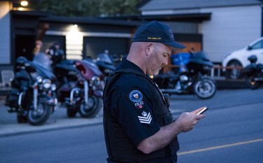 Sergeant Lindsey Houghton of The Combined Forces Special Enforcement Unit of British Columbia works from across the street of the Nanaimo Hells Angels clubhouse in Nanaimo on July, 20, 2018.