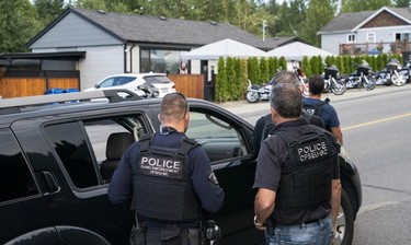 Members of The Combined Forces Special Enforcement Unit of British Columbia keep watch as members of the Hells Angels arrive at the Nanaimo Hell Angels' clubhouse in Nanaimo, BC, July, 21, 2018.