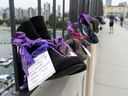 A pair of running shoes with a personal message hangs on the fence of Vancouver's Burrard Bridge on Aug.  30, 2020, as part of the awareness-raising art display Lost Soles: Gone Too Soon, with each pair of shoes representing a life lost to a drug overdose.