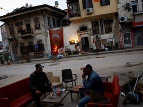 Mehmet Serkan Sincan, owner of an antique shop in central Antakya, and his friend Ben Hur Side hang out outside Sincan's damaged store in the aftermath of a deadly earthquake, in Antakya, Hatay province, Turkey, March 2, 2023. To maintain a sense of normalcy, Serkan Sincan has set up an exhibition outside the shop as he used to do in the past. REUTERS/Susana Vera