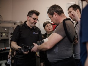 Nick Dechev (left) fits a man with a prosthetic arm at the Vinnytsia State Experimental Prosthetic and Orthopedic Enterprise in Vinnytsia, Ukraine in a handout photo.