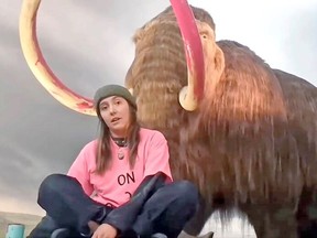A climate activist makes a statement after defacing the Royal B.C. Museum's woolly mammoth. VIA TWITTER