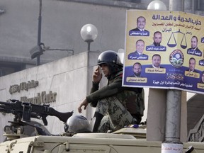 An Egyptian soldier sits on his armoured vehicle in front of a Freedom and Justice Party Arabic-language poster supporting Muslim Brothehood candidates outside a ballot counting centre in Giza, Egypt, Friday, Dec. 16, 2011. The party and the Brotherhood have since been outlawed. Egyptian asylum seekers spoke Monday alongside NDP MP Don Davies at his constituency office in Vancouver, decrying the CBSA's treatment of recent claimants affiliated with the Freedom and Justice Party and the potential denial of their refugee bids.