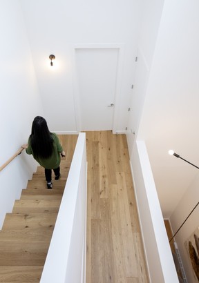 A hallway is designed with a half-wall overlooking the main living area, creating synergy and light flow between spaces.