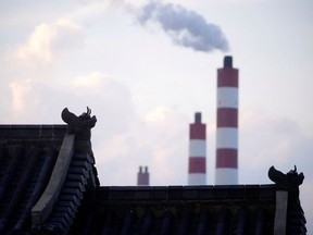 Chimneys of a coal-fired power plant are seen behind a gate in Shanghai in 2021.