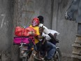 Residents travel on a motorbike as they flee their home to avoid clashes between armed gangs, in the Croix-des-Mission neighborhood of Port-au-Prince, Haiti, Thursday, April 28, 2022.