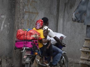 Residents travel on a motorbike as they flee their home to avoid clashes between armed gangs, in the Croix-des-Mission neighborhood of Port-au-Prince, Haiti, Thursday, April 28, 2022.