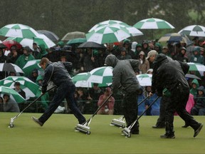 Greenskeepers remove standing water on the 18th green during the continuation of the weather delayed second round of the 2023 Masters Tournament.