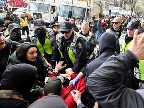 Vancouver Police push back protesters as city staff remove makeshift structures and tents belonging to people living in an encampment along East Hastings Street in the Downtown Eastside on Wednesday.