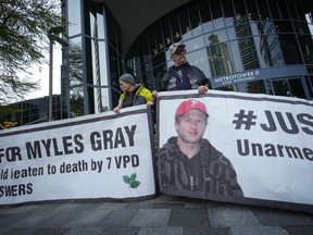 Protesters hold banners with a photograph of Myles Gray, who died following a confrontation with several police officers in 2015, before the start of a coroner's inquest into his death, in Burnaby, B.C., on Monday, April 17, 2023. The first officer to have an interaction with Myles Gray told a British Columbia coroner's inquest that she wasn't thinking about mental health and instead believed intoxication was driving the man's "bizarre" behaviour.
