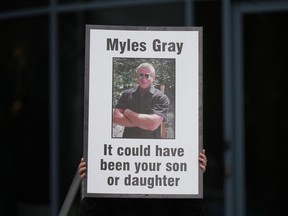 A person holds a sign with a photo of Myles Gray, who died following a confrontation with several police officers in 2015, before the start of a coroner's inquest into his death, in Burnaby, B.C., on Monday, April 17, 2023.