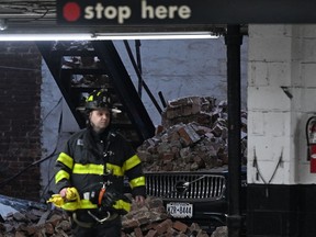 A member of the New York Fire Department (FDNY) walks past a car covered in rubble at the scene of a parking lot collapse in lower Manhattan, New York, April 18, 2023.