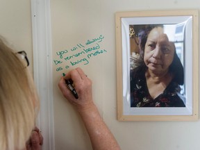 Tawow assistant manager Justine Davies, a former tenant support worker at the Winters Hotel, writes a message on the memorial for fire victim Mary Garlow on Tuesday. It has been one year since the Winters Hotel fire in Vancouver that killed two people and made dozens homeless.