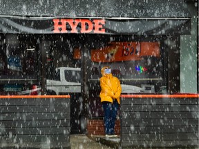 A person hides and takes cover from the hail pouring down on Main Street near 14th in Vancouver, BC., April 2, 2023.