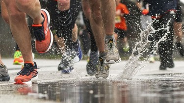 A runner lands in a puddle along Pacific Blvd in the 2023 Sun Run in Vancouver on April 16, 2023.