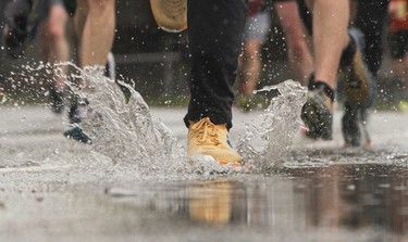 A runner lands in a puddle along Pacific Blvd in the 2023 Sun Run in Vancouver on April 16, 2023.