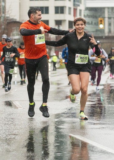 Alfredo Medina (left) and Karen Medina have some fun while running along Quebec Street and Pacific Blvd. in the 2023 Sun Run in Vancouver on April 16, 2023.