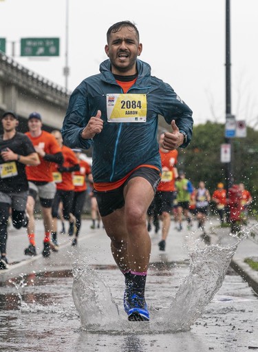 Aaron Rahim goes through a puddle while running towards the finish of the 2023 Sun Run in Vancouver on April 16, 2023.