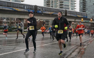 Teresa Tomchak (left) and Andy Smitten run along Pacific Blvd during the 2023 Sun Run in Vancouver on April 16, 2023.