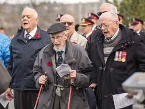 100-year-old Second World War veteran Angus Hamilton, centre, and Rev. Bob Jones, right, sing O Canada as part of the provincial Remembrance Day ceremony in Fredericton, Friday, Nov. 11, 2022. Three days before Hamilton turned 101, the Second World War veteran died peacefully at his home.