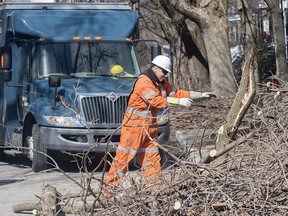 A Hydro worker clears fallen branches from a street following an ice storm in Montreal on Friday, April 7, 2023.
