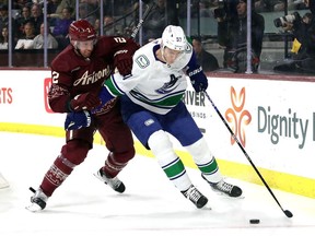 Tyler Myers of the Vancouver Canucks skates with the puck against Patrik Nemeth of the Arizona Coyotes during the first period at Mullett Arena on March 16, 2023 in Tempe, Arizona.