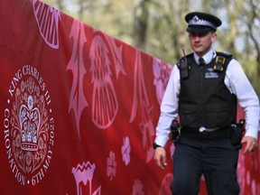 A police officer passes a partition displaying the Coronation Emblem near Buckingham Palace on Thursday, ahead of the coronation weekend.