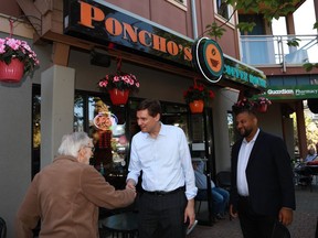 Premier David Eby and BC NDP candidate Ravi Parmar walk along Goldstream Ave. as they visit shops and talk to locals while out in Langford, B.C., on Thursday, May 25, 2023.
