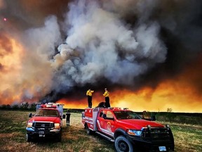 Firefighters stand on a Kamloops Fire Rescue truck at a wildfire near Fort St. John, British Columbia, Canada May 14, 2023.