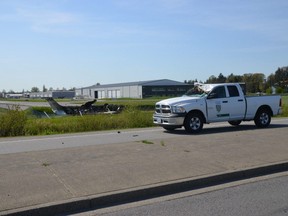 A Langley Township pickup truck is seen damaged after being hit by a plane, left, which crashed at the airport in Langley, B.C., Tuesday, May 2, 2023.