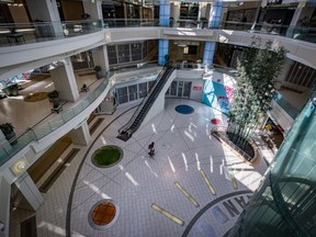 A man carries bags of groceries while walking through a deserted Metropolis at Metrotown shopping mall in Burnaby, B.C., on Sunday, April 12, 2020.