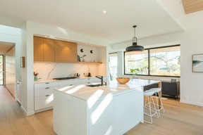 A concealed hood fan, integrated appliances and flush-set cabinetry keep the kitchen clean and modern, with dining chairs and stools from Vancouver Special.