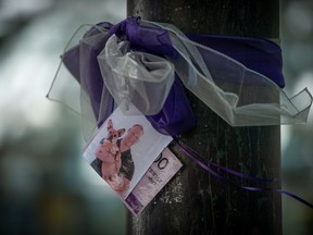 A photograph of a person who died due to an illicit drug overdose is tied to a tree with a purple ribbon by members of Moms Stop the Harm, in Vancouver, on Tuesday, August 16, 2022.