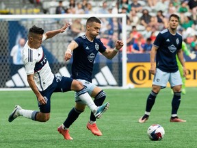 Vancouver Whitecaps' Andres Cubas slide tackles Sporting Kansas City's Erik Thommy during the first half of an MLS soccer match in Vancouver, on Saturday, June 3, 2023.