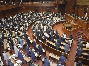 Japanese lawmakers stand as they approve an amended criminal law at the upper house in Tokyo Friday, June 16, 2023.