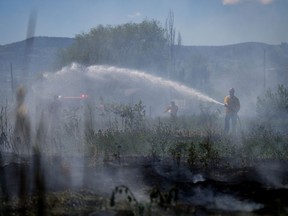 Firefighters battle a grass fire on an acreage behind a residential property in Kamloops, B.C., Monday, June 5, 2023. A small but aggressive wildfire on Vancouver Island is burning beside the only major highway linking Port Alberni, Tofino and Ucluelet to the rest of British Columbia.