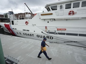 FILE - The U.S. Coast Guard Cutter Warren Deyampert is docked as a member of the Coast Guard walks past, Tuesday, June 20, 2023, at Coast Guard Base Boston, in Boston. Rescuers are racing against time to find the missing submersible carrying five people, who were reported overdue Sunday night, June 18, 2023.