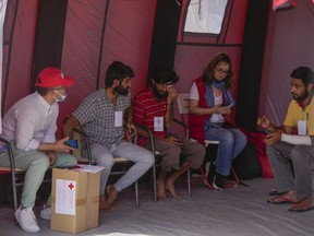 Survivors of a shipwreck speak with Red Cross volunteers outside a warehouse at the port in Kalamata town, about 240 kilometers (150miles) southwest of Athens, Thursday, June 15, 2023. A fishing boat crammed to the gunwales with migrants trying to reach Europe capsized and sank Wednesday June 14 off the coast of Greece, authorities said, leaving at least 79 dead and many more missing in one of the worst disasters of its kind this year.