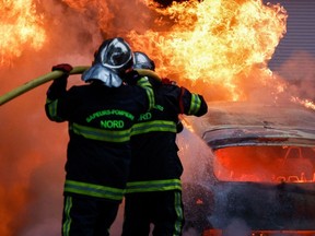 Firefighters put out a burning car during protests in Lille, northern France, on June 29.
