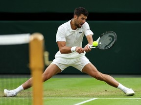 Serbia's Novak Djokovic slips while hitting a backhand against Italy's Jannik Sinner during semifinal action at Wimbledon on Friday. Djokovic won the match in straight sets.
