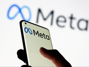 Woman holds smartphone with Meta logo in front of a displayed Facebook's new rebrand logo Meta in this illustration picture taken Oct. 28, 2021.