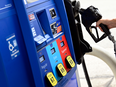 A person removes the nozzle from a pump at a gas station.