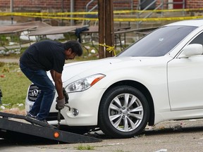 A tow truck operator removes a vehicle with multiple bullet holes near the area of a mass shooting in Baltimore, Sunday, July 2, 2023.