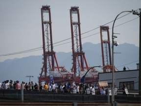 Striking International Longshore and Warehouse Union Canada workers march to a rally as gantry cranes used to load and unload cargo containers from ships sit idle at port in Vancouver on Thursday, July 6, 2023. Thousands of workers at British Columbia's ports will take off the day shift today to learn the details of an agreement struck between their union and employers.