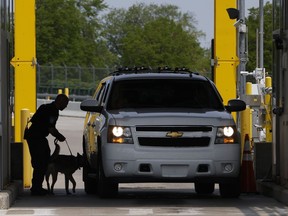 A U.S. Customs and Border Protection officer canine unit searches a vehicle as motorists pass through the Peace Bridge Port of Entry in Buffalo, N.Y. on Tuesday, May 23, 2023.