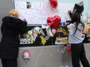 Women sign a memorial to 21-year-old Tristan Asham outside Smokin' Aces, a restaurant/nightclub on McDermot Avenue in Winnipeg on Sunday, Nov. 6, 2022. Police said Asham was shot and killed early Saturday morning on McDermot and the homicide unit has taken over the investigation.